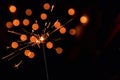 Magic burning sparkler. Dark background with blurred lights of Christmas garland. Copy space on the right. Royalty Free Stock Photo