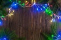 Magic Christmas garland with bright lights and fir tree branches on wooden background Royalty Free Stock Photo