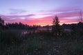 Magic colourful sunrise by the lake with morning fog. Dark silhouette of trees and water with colourful reflections. Beautiful