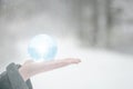 Magic crystal ball with a fantastic flare on the palm in a snowy forest Royalty Free Stock Photo