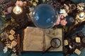 Magic crystal ball, tarot cards and book for spells on witch ritual table. Royalty Free Stock Photo