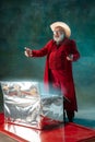 Modern stylish Santa Claus in red fashionable suit and cowboy`s hat on dark background Royalty Free Stock Photo