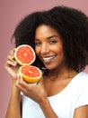 The magic is inside. Studio shot of an attractive young woman eating grapefruit against a pink background. Royalty Free Stock Photo
