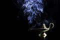 Magic lamp from the story of Aladdin with Genie appearing in blue smoke concept for wishing, luck and magic Royalty Free Stock Photo