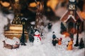 Magic Little Christmas city in miniature with snow,snowman, lights, people and children toys, trees and old building. Stylish