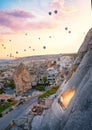 Magic morning in Cappadocia - a woman on the cave balcony watching an amazing morning flight of balloons