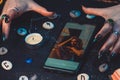 Magic and online fortune telling. The hands of a witch and fortune teller cast a spell over a photo on a smartphone. Close up