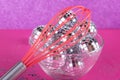 Magic party concept. Small toy discoballs in glass plate and kitchen whisk on purple, pink background. Small silver stars around.