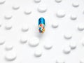 Magic pill concept. A large tablet capsule with multi-colored filling is in the center of white tablets on a background