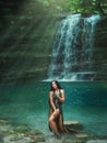 Magic tropical nature, dark-haired girl comes out of the azure transparent clear waterfall lake water, sea nymph in Royalty Free Stock Photo