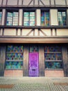 Magic wooden purple door. Beautiful house facade with colorful windows glass and pavement yard. Vintage architecture