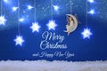 Magical christmas image of little white fairy with glitter wings sitting on the moon over blue background and silver snowflake gar Royalty Free Stock Photo