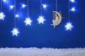 Magical christmas image of little white fairy with glitter wings sitting on the moon over blue background and silver snowflake gar Royalty Free Stock Photo