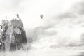 Magical hot-air balloon flies in the clouds above the mountain peaks