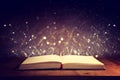 Magical image of open antique book over wooden table with glitter overlay Royalty Free Stock Photo
