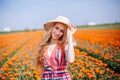 Beautiful young long red hair woman wearing in striped dress and straw hat standing on colorful flower tulip field in Holland Royalty Free Stock Photo