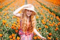 Beautiful young long red hair woman wearing in striped dress and straw hat standing on colorful flower tulip field in Holland Royalty Free Stock Photo