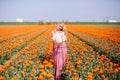 Beautiful young long red hair woman wearing in striped dress and straw hat standing on colorful flower tulip field in Holland Royalty Free Stock Photo