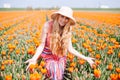 Beautiful young long red hair woman wearing in striped dress and straw hat standing on colorful flower tulip field in Holland Royalty Free Stock Photo