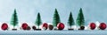 Magical miniature winter wonderland banner. Evergreen trees, pine cones and red christmas baubles on shiny blue background.