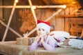 A magical photo of a little girl at home on the bed under Christmas. Portrait of a girl in a pink sweater close-up with a hat of S