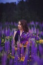 A magical portrait of a young girl in a gradient dress in a purple-pink lupine field at twilights. Royalty Free Stock Photo