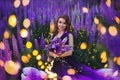 A magical portrait of a young girl in a gradient dress in a purple-pink lupine field at twilights. Royalty Free Stock Photo