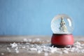 Magical snow globe with Christmas tree on table against color background. Space for text Royalty Free Stock Photo