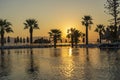 Magical sunrise with silhouette coconut palm tree and swimming pool in luxury hotel resort near sea. Beautiful morning seascape Royalty Free Stock Photo