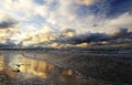 A magical sunset on the sea coast, storm clouds highlighted by the golden light of the setting sun, a sandy beach reflects the col Royalty Free Stock Photo