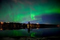 A magical view of aurora borealis with a city scape under starry clear sky and reflection from lake water in ascandenevia Royalty Free Stock Photo