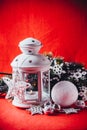 Magical white lantern is standing with white knit star on it and a fir tree branch and a snowball on a christmas red background. Royalty Free Stock Photo