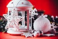 Magical white lantern is standing with white knit star on it and a fir tree branch and a snowball on a christmas red background. Royalty Free Stock Photo