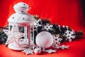 Magical white lantern is standing with white knit star on it and a fir tree branch and a snowball on a christmas red background. Royalty Free Stock Photo