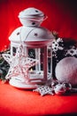 Magical white lantern is standing with white knit star on it and a fir tree branch and a snowball on a christmas red background. Royalty Free Stock Photo