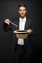 A magician in a black suit holding an empty top hat