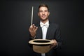 A magician in a black suit holding an empty top hat Royalty Free Stock Photo