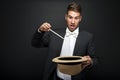 A magician in a black suit holding an empty top hat Royalty Free Stock Photo