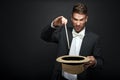 A magician in a black suit holding an empty top hat