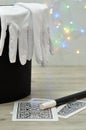 A magician hat with a pair of gloves and a wand with an out of focus background