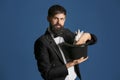 Magician holding hat with rabbit on color background Royalty Free Stock Photo