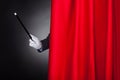 Magician holding wand behind stage curtain