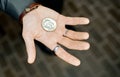 Magician holds the coin before focusing on the open palm against the background of the tile Royalty Free Stock Photo