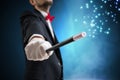 Magician or illusionist is showing magic trick. Blue stage light in background Royalty Free Stock Photo