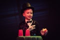 Magician kid illusionist boy in hat. wizard mystery black background