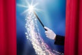 Magician`s Hand Holding Magic Wand Behind Curtain