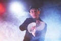 Magician showing trick with playing cards. Magic or dexterity, circus, gambling. Prestidigitator in dark room with fog Royalty Free Stock Photo