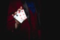 Magician shows focus, holds two playing cards in hand, copy space black background