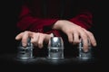 Magician shows shell game of thimbles with circles and ball, black background. Concept deception, sleight hand