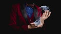 Magician shows trick with playing cards on dark background, concept stand-up